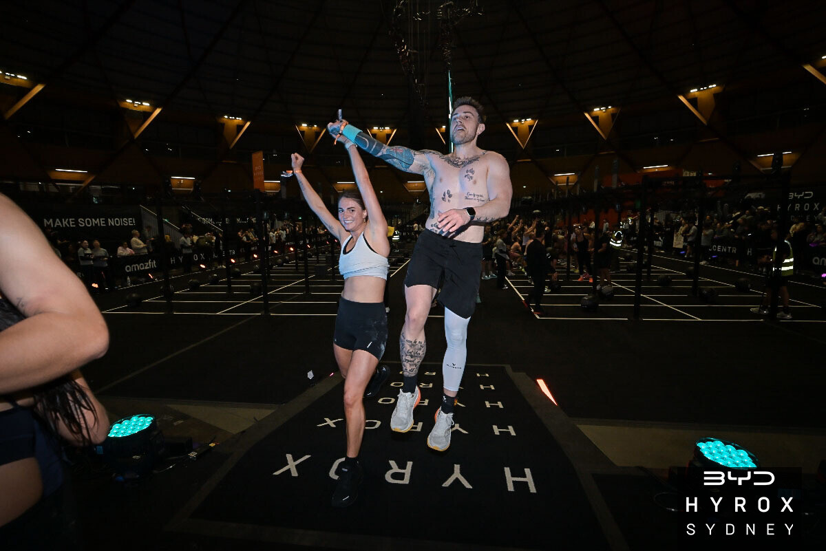 Athlete celebrating at the finish line after hybrid race preparation